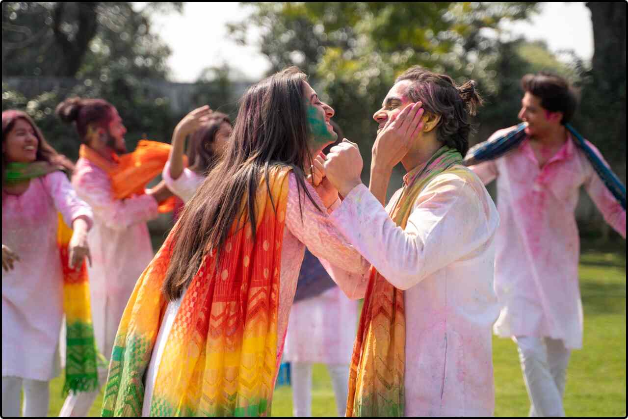 Group of joyful people covered in colorful powders, celebrating Holi festival.